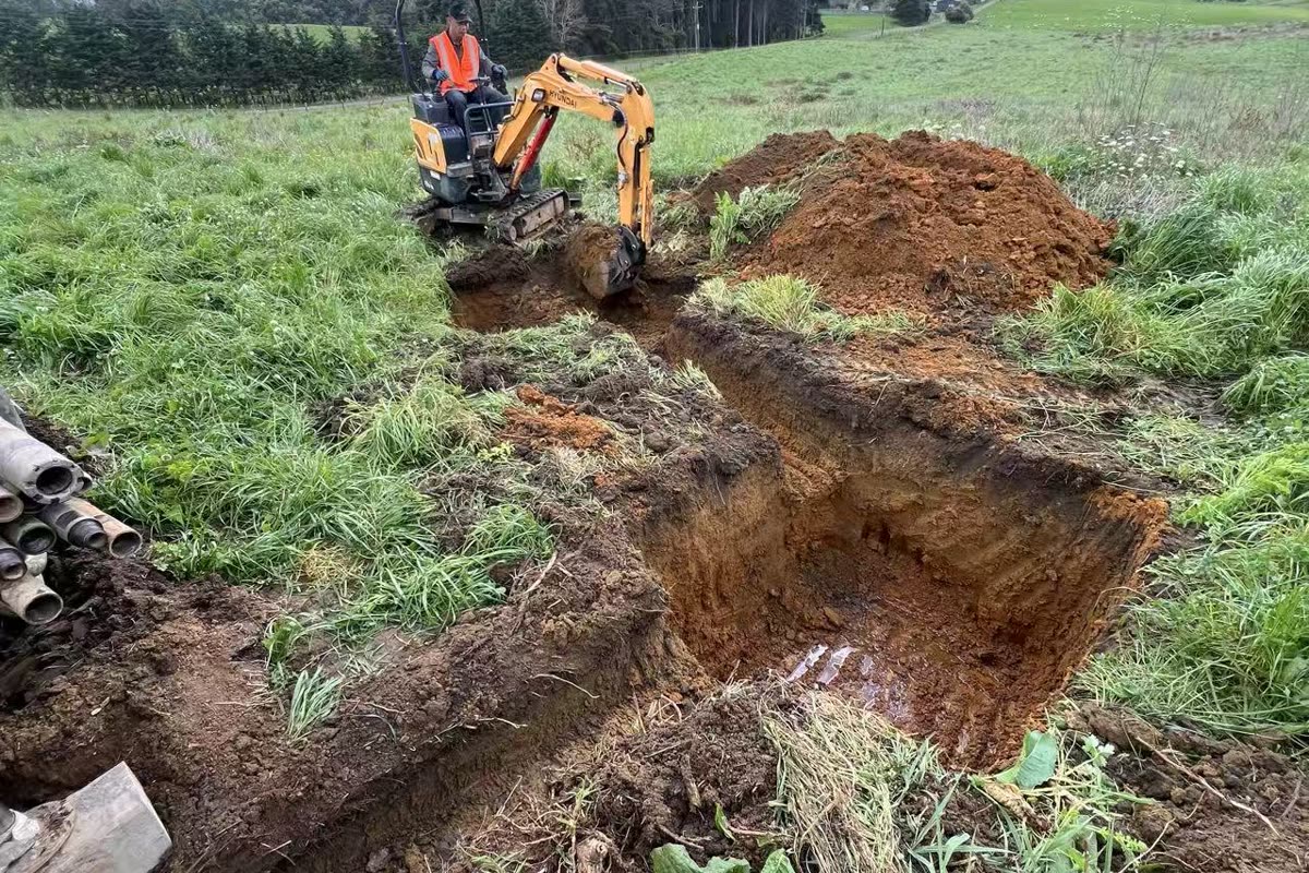 Excavator exposing ground conditions in a test pit
